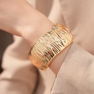 Detailaufnahme eines goldfarbenen Armreifs mit einem plissierten geometrischen Design.