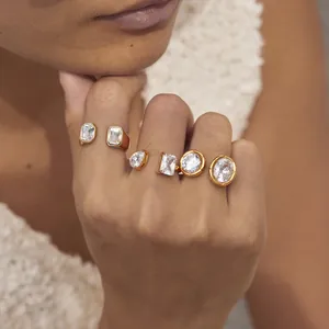 Detail of gold stainless steel ring set with various zircon shapes on female hand.