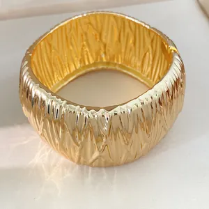 Nahaufnahme des luxuriösen goldfarbenen Armreifs mit einzigartiger Faltenstruktur-Detail