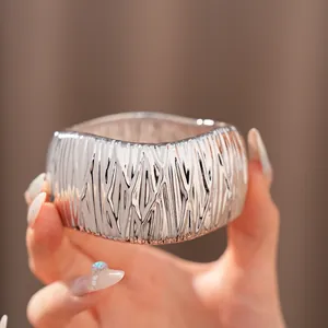 Detailansicht eines glänzenden silbernen Manschettenarmbands mit Faltenstruktur