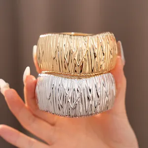 Nahaufnahme geometrischer Armreifen mit Rippstruktur in Gold und Silber