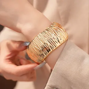Detailansicht der strukturierten Oberfläche eines massiven goldenen Armreifs am Arm