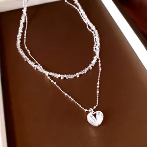 Collier double épaisseur avec perles de cristal et pendentif cœur en zircon brillant.