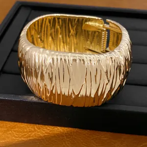 Nahaufnahme eines hochwertigen goldfarbenen Armreifs mit einzigartigem Faltenstruktur-Design