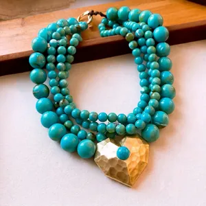 Meerrijige ketting van turquoise kralen met gehamerde gouden hart hanger en OT-sluiting.