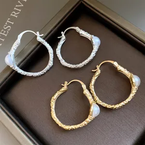 Detailansicht der gold- und silberfarbenen Creolen mit Perlen und Retro-Textur..