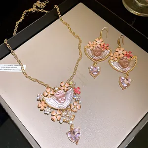 Detail des Vintage-Schmucksets mit Cherub-Motiv, Blumen aus Harz und Herzanhängern.