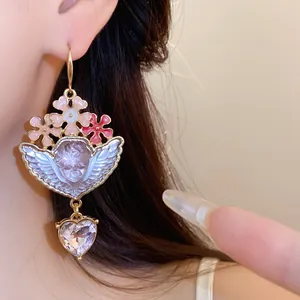 Nahaufnahme eines Vintage-Ohrrings mit Harz-Engel und herabhängendem Kristallherz.