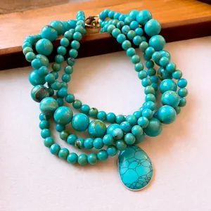 Meerlaagse turquoise kralenketting met grote druppelhanger en een stijlvolle OT-sluiting