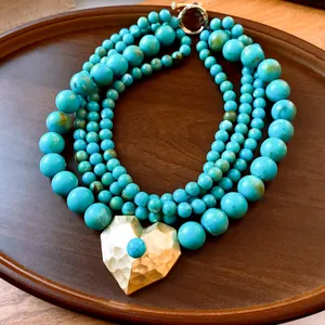 Detailopname van een meerlaagse turquoise kralenketting met een gouden harthanger
