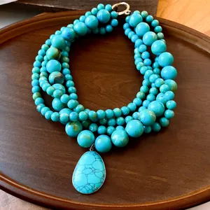 Detailweergave van meerstrengs turquoise kralenketting met een grote druppelhanger