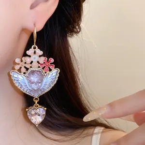 Nahaufnahme von Vintage-Barock-Ohrringen mit Harz-Putte und baumelndem Herz-Strass-Detail