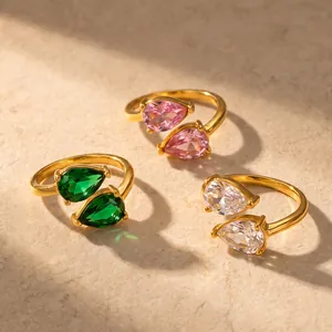 Detail view of three colors of stainless steel teardrop zircon rings in soft sunlight.