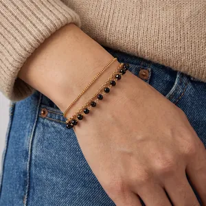 Gros plan d'un élégant bracelet en acier inoxydable plaqué or 18k avec perles noires.