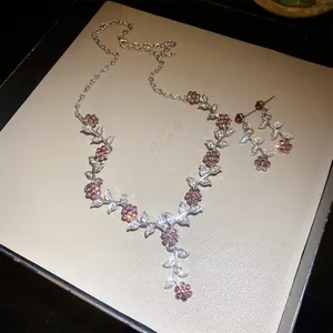 Detailweergave van de fonkelende halsketting en oorbellen set met blad- en bloemhangers
