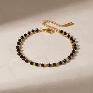 Détail rapproché d'un bracelet en acier inoxydable plaqué or 18 carats et perles noires.