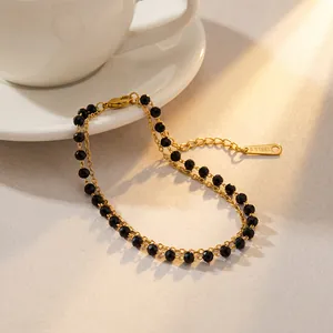 Détail d'un élégant bracelet en acier inoxydable plaqué or avec perles noires