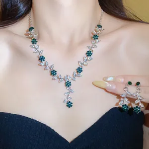 Detailweergave van smaragdgroene bloem en zilveren blad strass ketting en oorbellen set