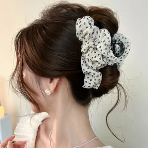 Détail d'une pince à cheveux romantique en tissu floral blanc portée sur un chignon élégant