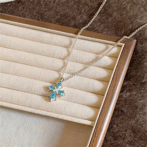 Gedetailleerde weergave van een zilveren kruis ketting met blauwe zirkonia stenen