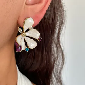 Detail view of elegant white floral drip oil earring with colorful rhinestones on model