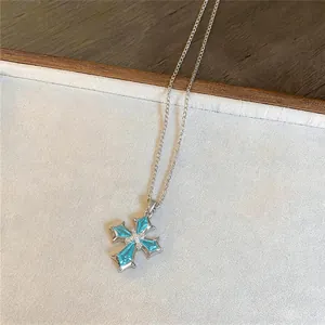 Close-up van een glinsterende lichtblauwe zirkoon kruis hanger ketting aan zilveren ketting