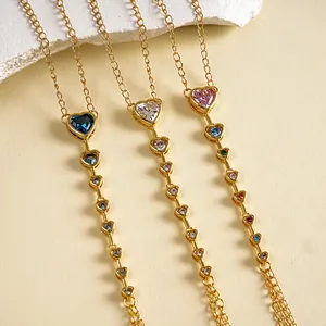 Detailopname van drie 18k vergulde hart-zirkonia kettingarmbanden op een beige ondergrond