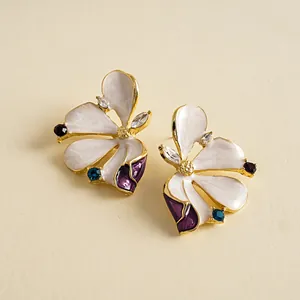 Close-up detail of elegant floral enamel stud earrings with colorful rhinestone accents