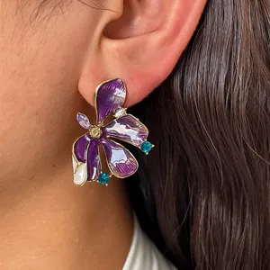 Detailed close-up shot of elegant purple floral enamel stud earrings with shimmering crystal accents