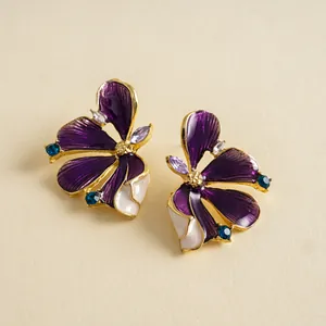 Detailed macro view of purple enamel flower stud earrings with shimmering blue rhinestones