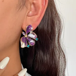Close-up of elegant purple flower enamel stud earring with colorful rhinestones on model ear