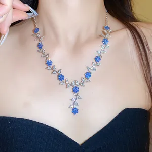 Detailweergave van de elegante ketting met blauwe bloemen en zilveren bladeren op een model