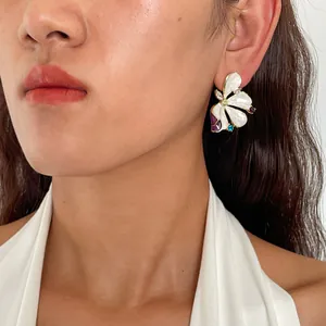 Close-up of elegant flower enamel stud earrings with rhinestones on model