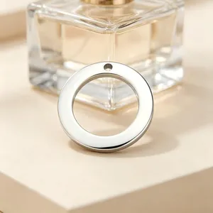 Macro view of a smooth, polished stainless steel circular pendant with a single hole