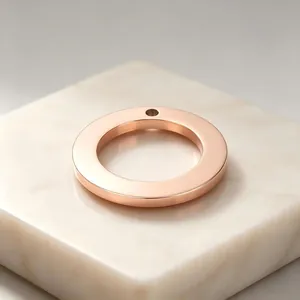 Close-up of a rose gold stainless steel round pendant ring with a single hole for DIY jewelry