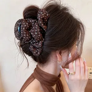 Close-up of elegant brown floral fabric hair claw clip on a messy bun hairstyle.