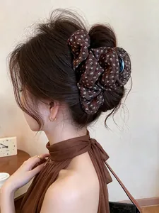 Detailed view of a vintage-style brown floral fabric-covered hair claw clip in use.