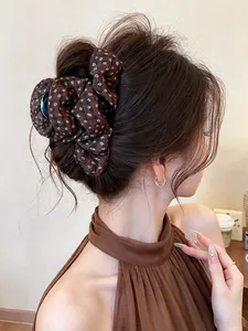 Close-up detail of a vintage brown floral fabric hair claw clip styled on a model's hair bun