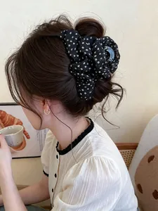 Close-up of elegant black floral fabric hair claw clip in a stylish bun hairstyle