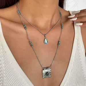 Gros plan de colliers superposés en acier inoxydable avec pendentifs en résine