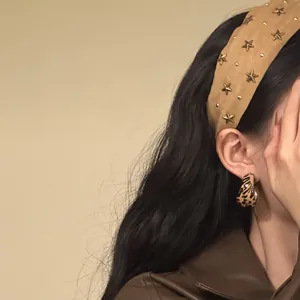 Verfijnd detail van een vintage stoffen hoofdband met gouden sterren op een model
