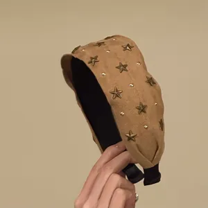 Macrodetail van een vintage kameelkleurige suède hoofdband met bronzen sterstuds