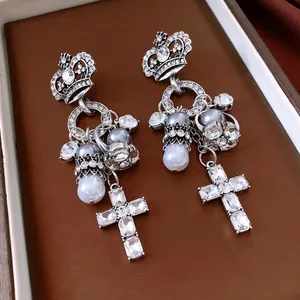 Detailansicht luxuriöser Kronenohrringe mit Kunstperlen und Kristallkreuzanhängern.