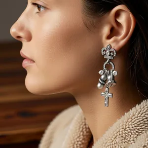 Detailansicht eleganter Silberohrringe mit Krone, Kreuz und Perlen an einem Model