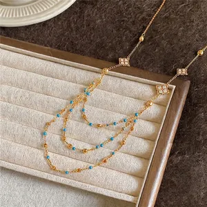 Elegant layered gold chain necklace with blue beads and zircon rhombus accents on tray
