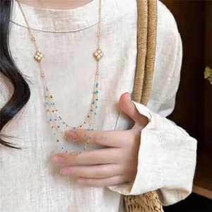 Elegant gold-tone necklace with zircon rhombus charms and blue beaded layers.
