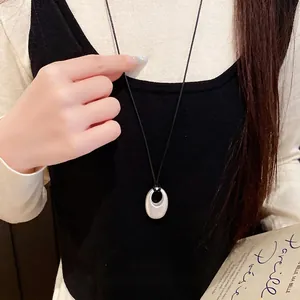 Eleganter silberner ovaler Anhänger an einer schwarzen Lederkordel Kette am Modell