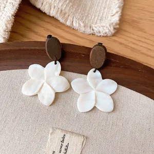 Detailed macro shot of vintage white flower earrings with brown wooden oval studs
