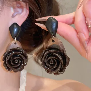 Close-up of vintage dark rose earrings featuring a glossy finish and wood texture