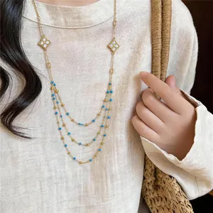 Detailed view of elegant multi-layer gold necklace with blue beads and zircon charms